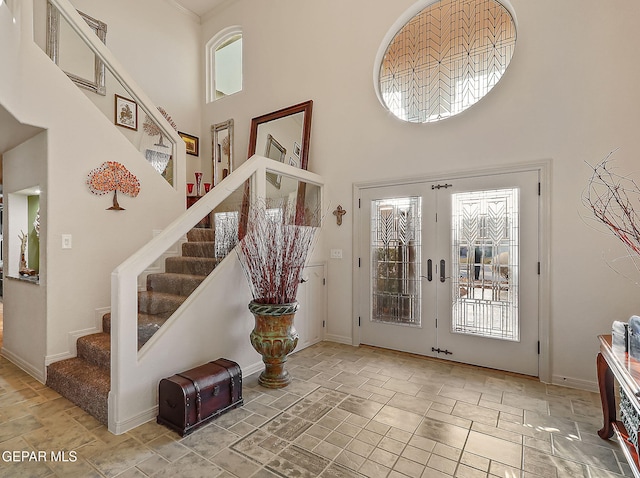 foyer featuring a towering ceiling, a wealth of natural light, and french doors