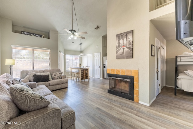 living room with a fireplace, hardwood / wood-style flooring, high vaulted ceiling, and ceiling fan