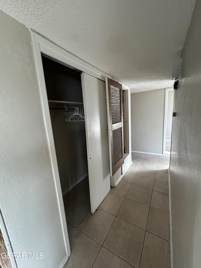 corridor with light tile patterned floors and a textured ceiling