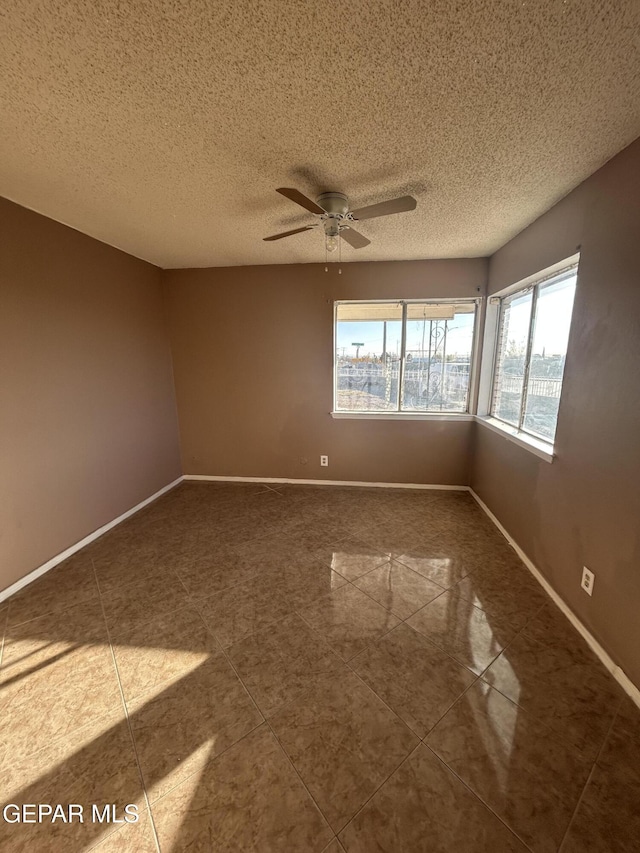 empty room featuring tile patterned floors, ceiling fan, and a textured ceiling