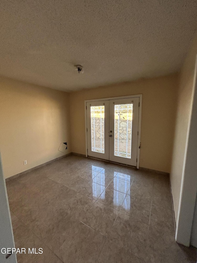 unfurnished room featuring french doors and a textured ceiling