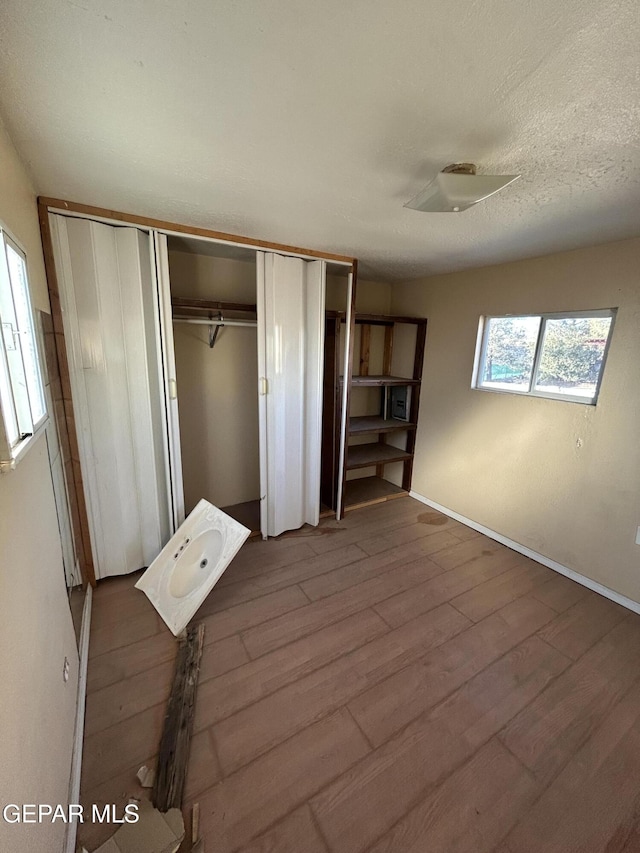 unfurnished bedroom featuring a closet, wood-type flooring, and a textured ceiling