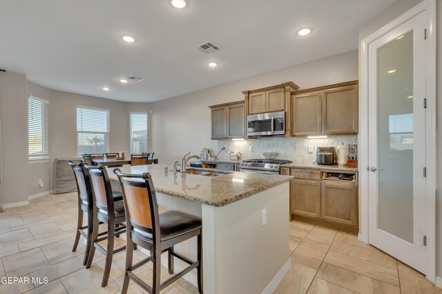 912 Crystal Deer Dr, El Paso, TX 79928 - kitchen with sink, stainless steel appliances, tasteful backsplash, an island with sink, and a breakfast bar