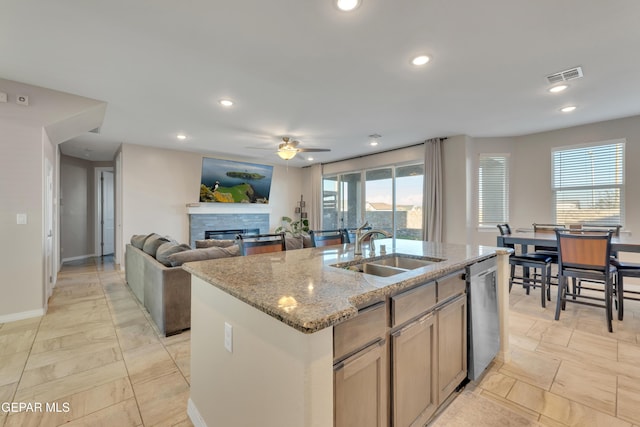 912 Crystal Deer Dr, El Paso, TX 79928 - kitchen featuring dishwasher, a glass covered fireplace, a ceiling fan, a kitchen island with sink, and light stone counters