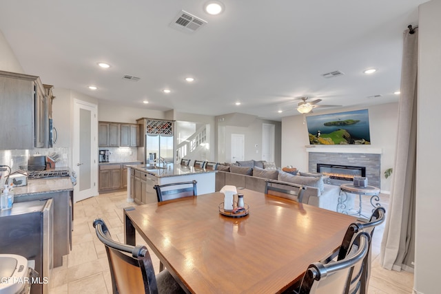 912 Crystal Deer Dr, El Paso, TX 79928 - tiled dining room with a stone fireplace, ceiling fan, and sink
