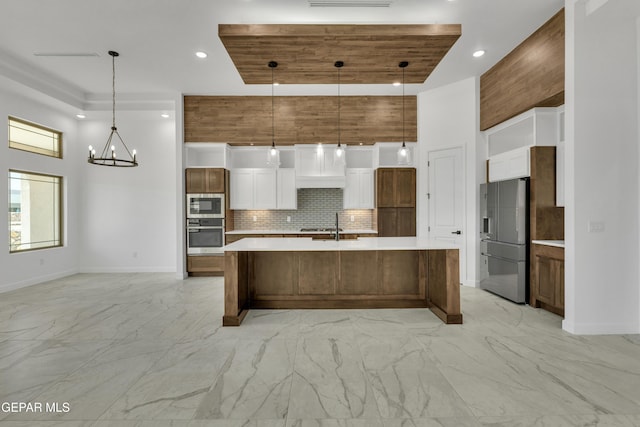 kitchen featuring appliances with stainless steel finishes, tasteful backsplash, white cabinetry, and hanging light fixtures