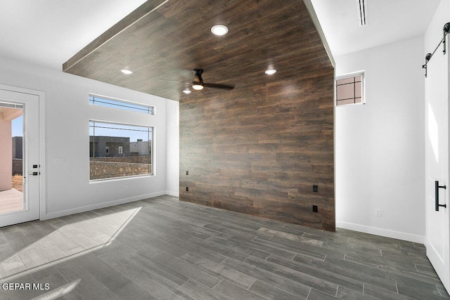 spare room featuring dark hardwood / wood-style flooring, a barn door, and ceiling fan