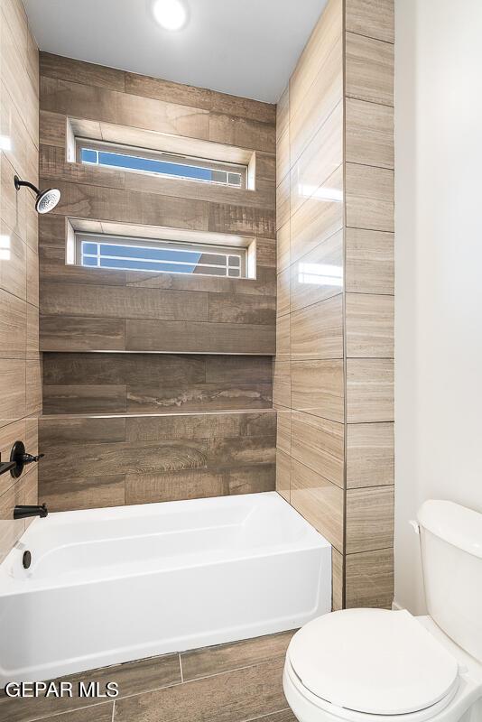 bathroom featuring tiled shower / bath combo and toilet