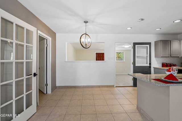 kitchen featuring backsplash, light tile patterned floors, decorative light fixtures, and a notable chandelier