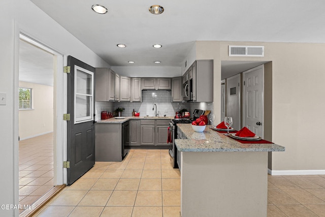 kitchen featuring light stone counters, gray cabinets, light tile patterned flooring, and stainless steel appliances