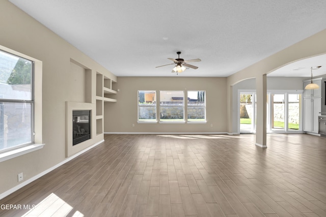 unfurnished living room with wood-type flooring, ceiling fan, and a healthy amount of sunlight