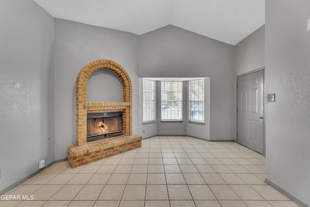 unfurnished living room featuring a fireplace, light tile patterned flooring, and high vaulted ceiling