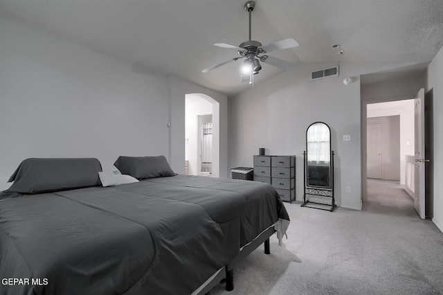 carpeted bedroom with a textured ceiling, vaulted ceiling, and ceiling fan