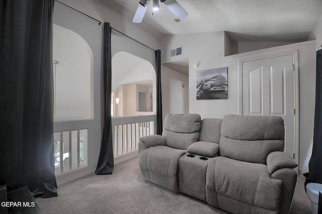 living room with vaulted ceiling, carpet floors, ceiling fan, and a textured ceiling