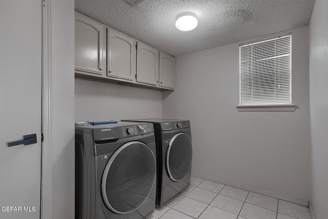 laundry area featuring cabinets, washer and dryer, light tile patterned floors, and a textured ceiling