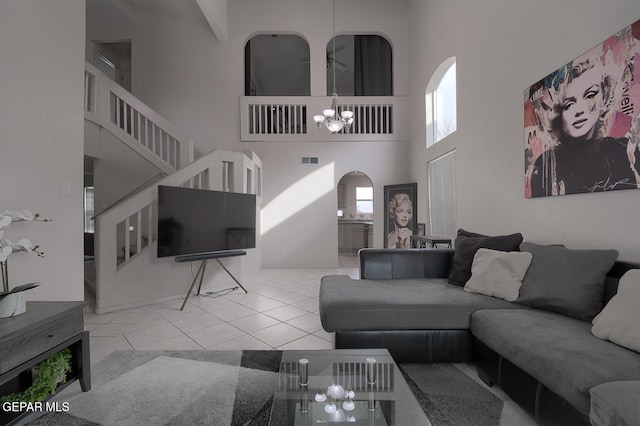 living room featuring light tile patterned flooring, a notable chandelier, and a high ceiling