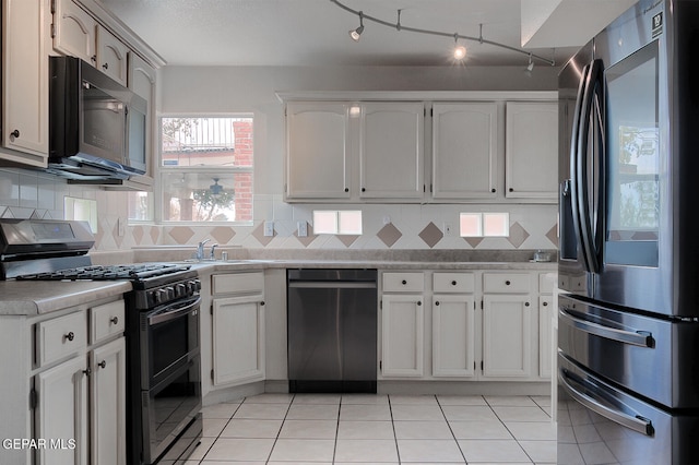 kitchen featuring stainless steel appliances, sink, light tile patterned floors, and white cabinets