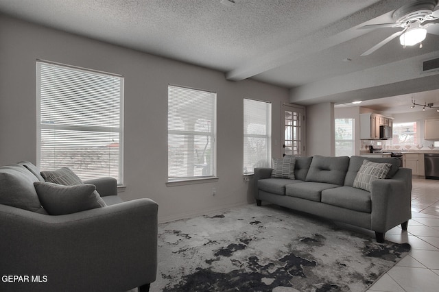 tiled living room with ceiling fan, beam ceiling, and a textured ceiling