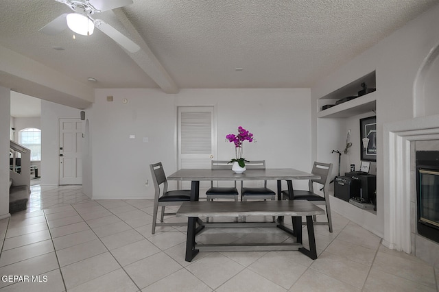 tiled dining area featuring beamed ceiling, a textured ceiling, and built in shelves