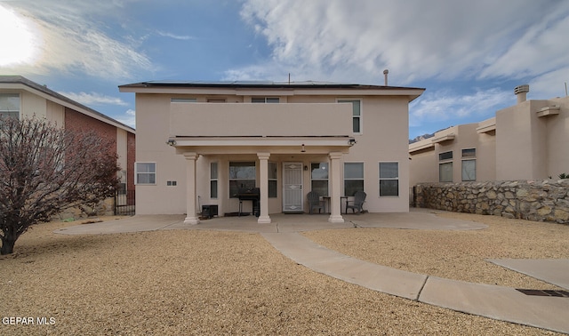 rear view of house featuring a balcony, a wall mounted air conditioner, a patio, and solar panels