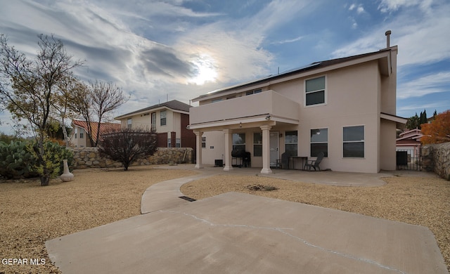 rear view of house featuring a balcony and a patio