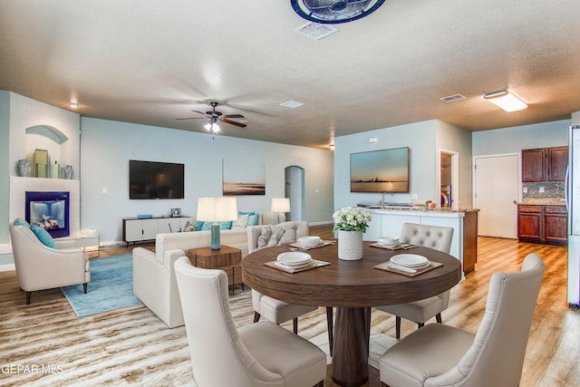 dining room with ceiling fan, light hardwood / wood-style flooring, a textured ceiling, and sink