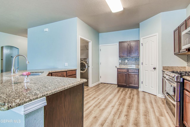 kitchen featuring sink, kitchen peninsula, light hardwood / wood-style floors, double oven range, and washer / dryer