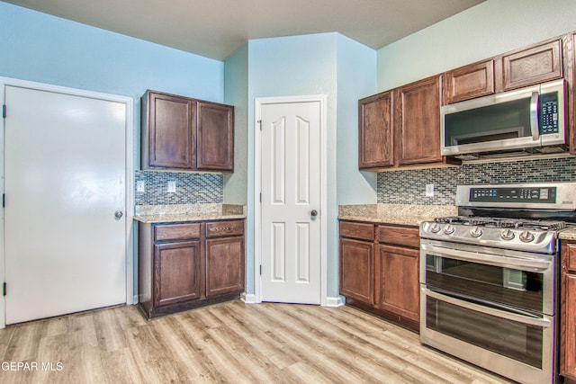 kitchen featuring light stone countertops, decorative backsplash, light hardwood / wood-style flooring, and stainless steel appliances