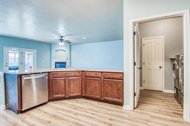 kitchen with stainless steel dishwasher, a textured ceiling, sink, washing machine and clothes dryer, and light hardwood / wood-style floors