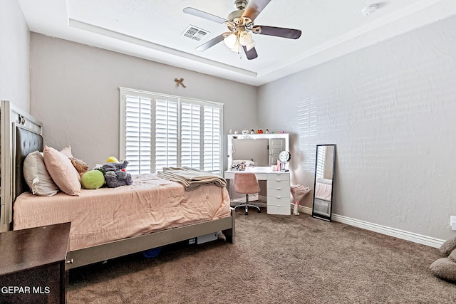 carpeted bedroom featuring a raised ceiling and ceiling fan