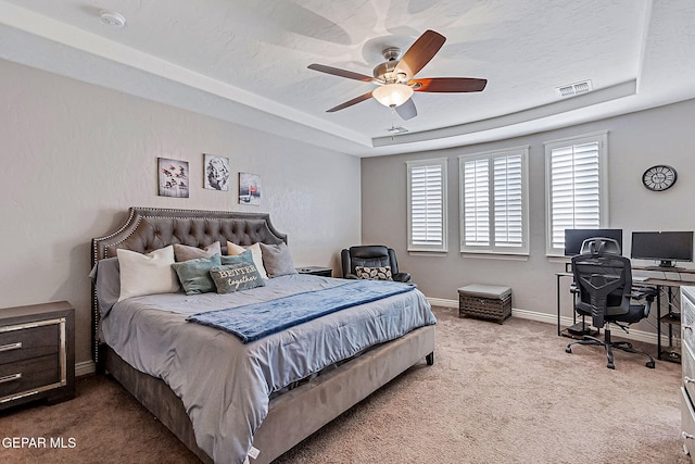 carpeted bedroom featuring ceiling fan and a raised ceiling