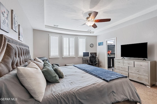 bedroom featuring a closet, carpet floors, a tray ceiling, and ceiling fan