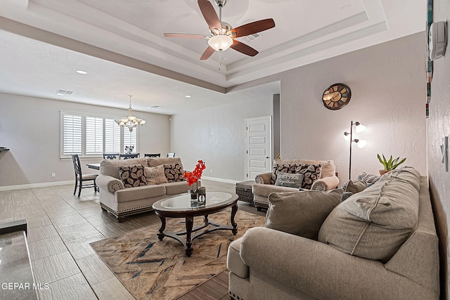 living room featuring hardwood / wood-style floors, ceiling fan with notable chandelier, and a raised ceiling