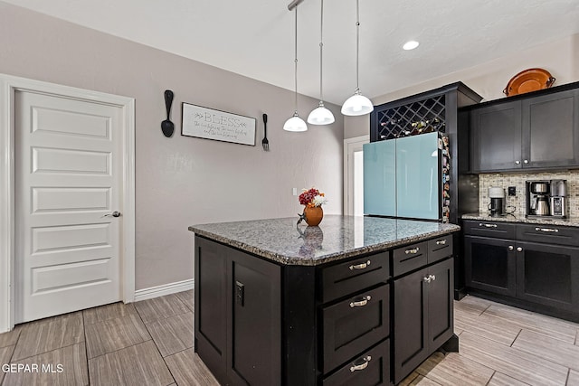 kitchen featuring stainless steel fridge, backsplash, decorative light fixtures, stone countertops, and a center island