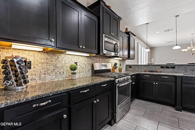 kitchen featuring dark stone countertops, stainless steel appliances, hanging light fixtures, and tasteful backsplash