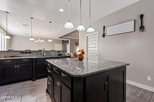 kitchen with a center island, pendant lighting, light wood-type flooring, and sink