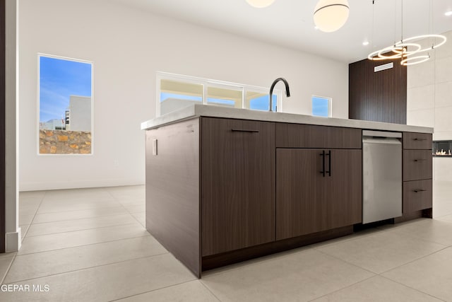 kitchen with a healthy amount of sunlight, dark brown cabinets, light tile patterned floors, and hanging light fixtures