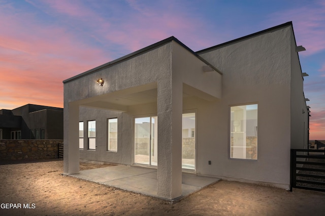 back house at dusk featuring a patio