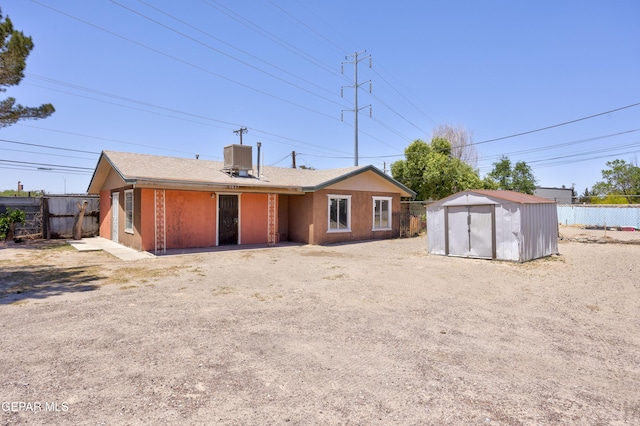 back of house with a storage shed and central AC