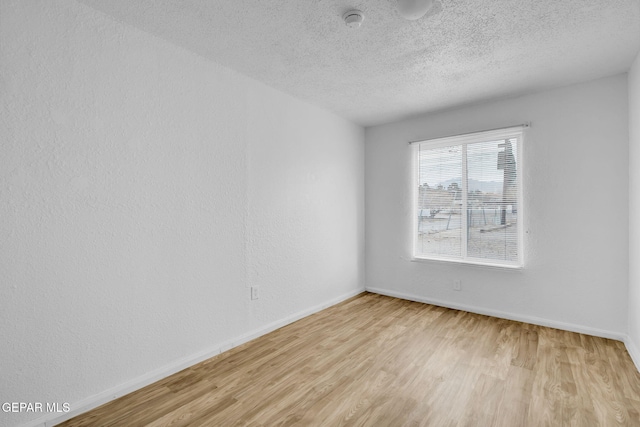 empty room with light hardwood / wood-style flooring and a textured ceiling