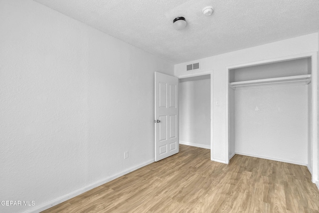 unfurnished bedroom featuring light hardwood / wood-style floors, a closet, and a textured ceiling
