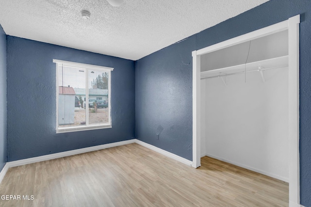 unfurnished bedroom with light hardwood / wood-style flooring, a textured ceiling, and a closet