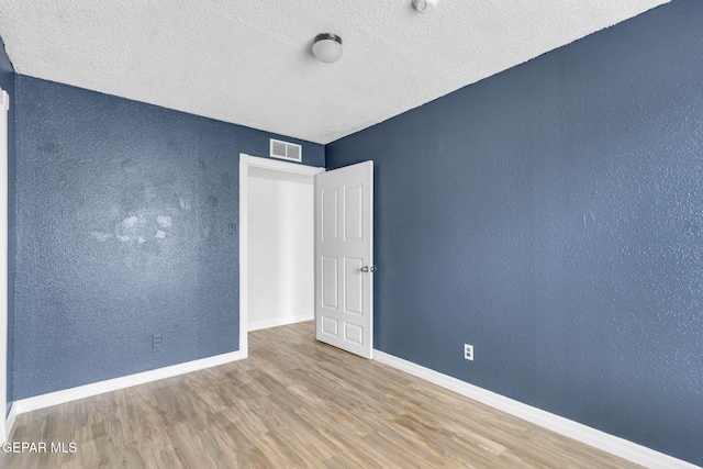 spare room with hardwood / wood-style floors and a textured ceiling