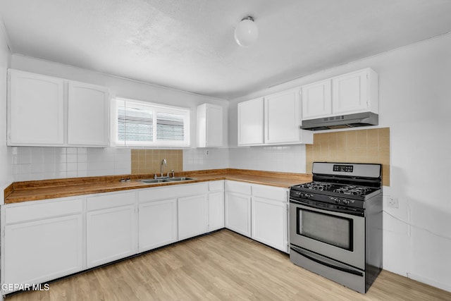 kitchen with wooden counters, sink, gas stove, and white cabinets