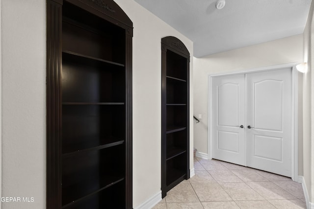 hall featuring light tile patterned flooring and a textured ceiling