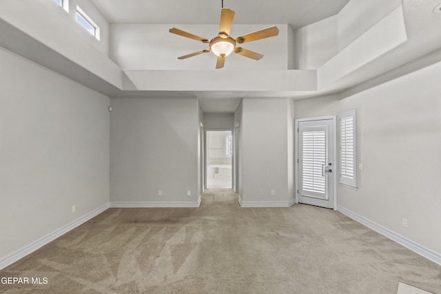 empty room with plenty of natural light, light colored carpet, and a high ceiling