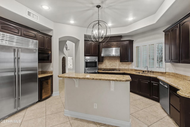 kitchen featuring appliances with stainless steel finishes, dark brown cabinetry, decorative light fixtures, and a kitchen island