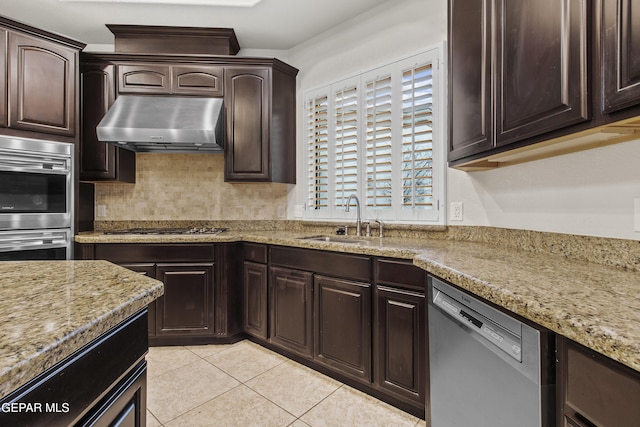 kitchen with exhaust hood, sink, light stone countertops, dark brown cabinetry, and stainless steel appliances