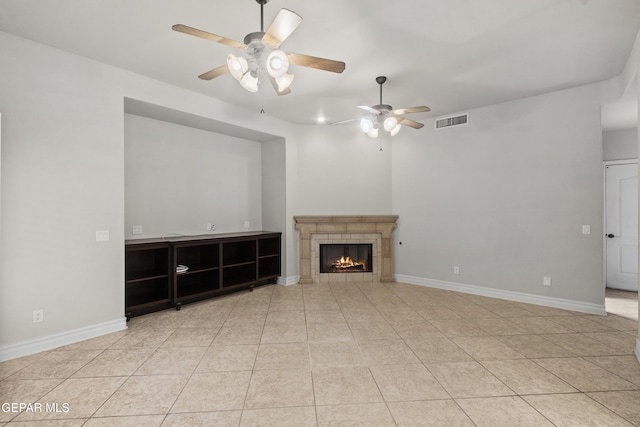 unfurnished living room with a fireplace, light tile patterned floors, and ceiling fan