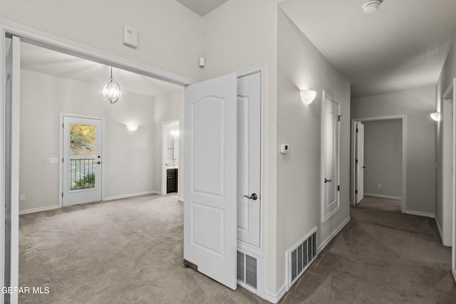 hall with a chandelier and light colored carpet